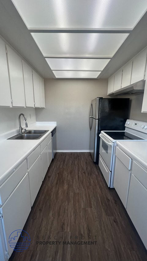 A kitchen with white cabinets and a black fridge.