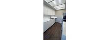 A kitchen with white cabinets and a wooden floor.