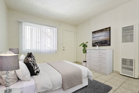 A bedroom with a bed, nightstand, and a painting on the wall.