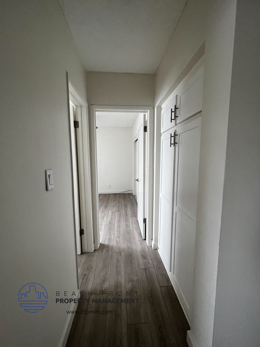 a black and white photo of a hallway with white walls and wood floors