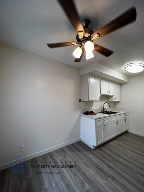 a kitchen with white cabinets and a ceiling fan
