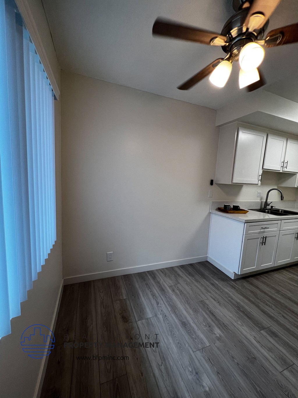 an empty room with a large window and a ceiling fan