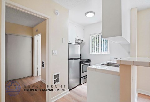 A kitchen with a refrigerator, oven, and sink.