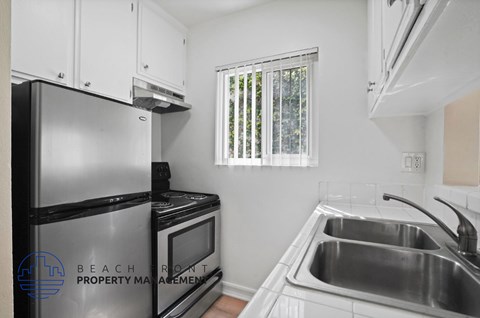 A kitchen with a black refrigerator, stove, and microwave.