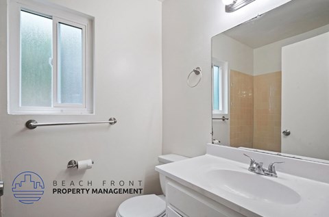A white bathroom with a toilet, sink, and mirror.