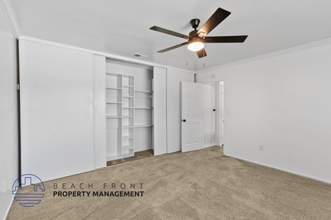 A spacious room with a ceiling fan and carpeted floor.