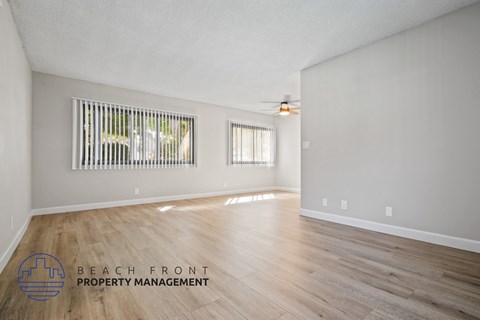 A spacious room with wooden flooring and a ceiling fan.