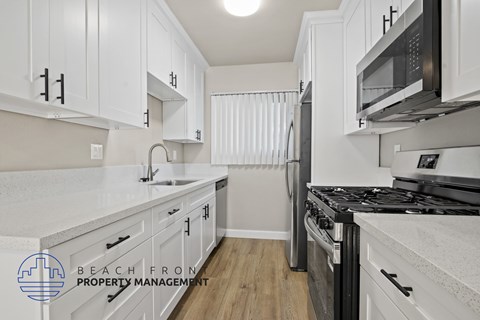 A kitchen with white cabinets and a black stove top oven.