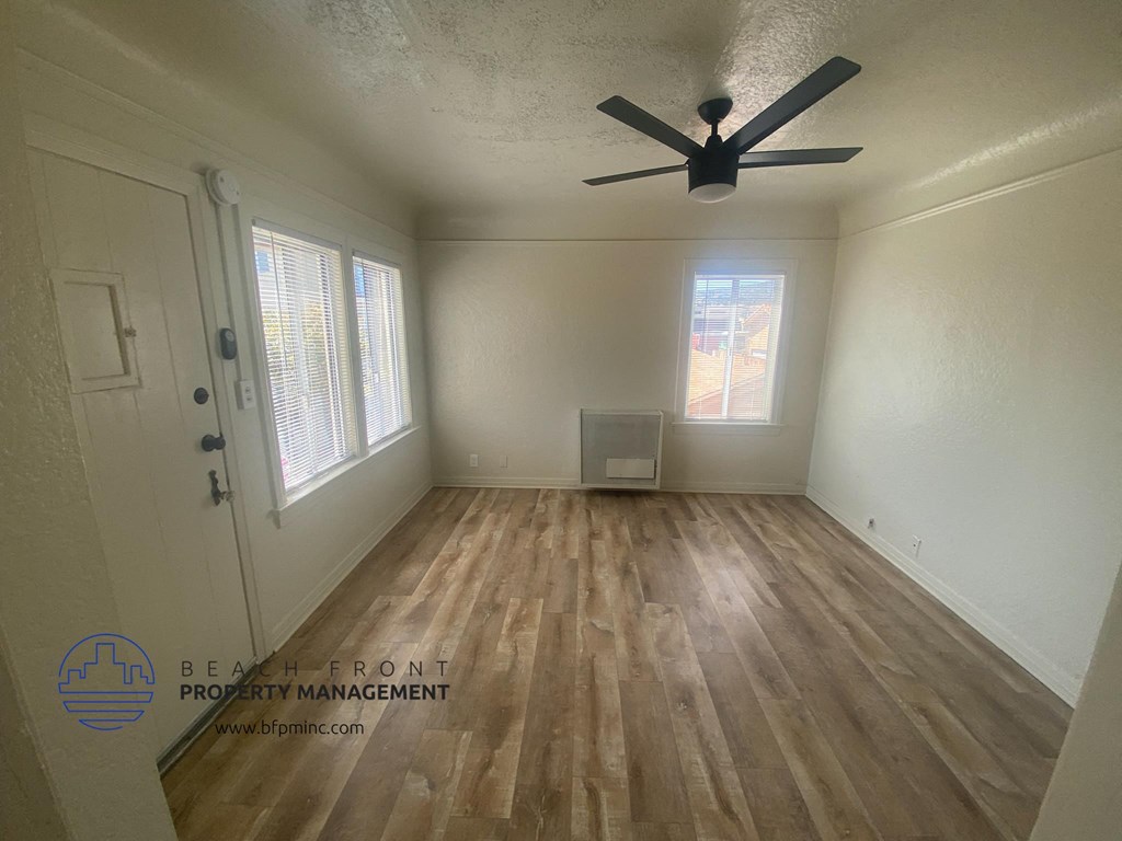the interior of an empty room with wooden floors and a ceiling fan