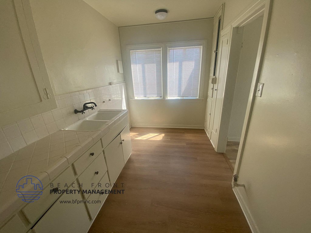 a kitchen with white cabinets and a sink and a window