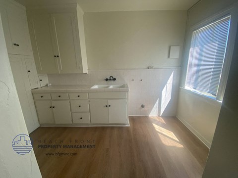 a small kitchen with white cabinets and a sink and a window