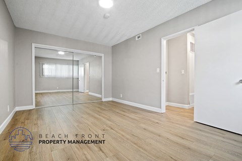 A spacious room with a large mirror and wooden flooring.