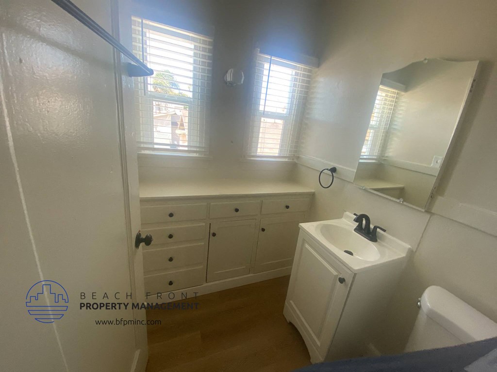 a small bathroom with white cabinets and a sink and a mirror