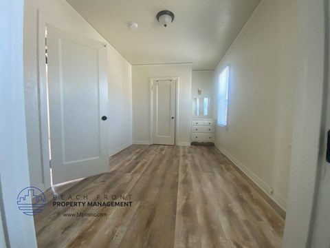 A hallway with wooden floors and white walls.