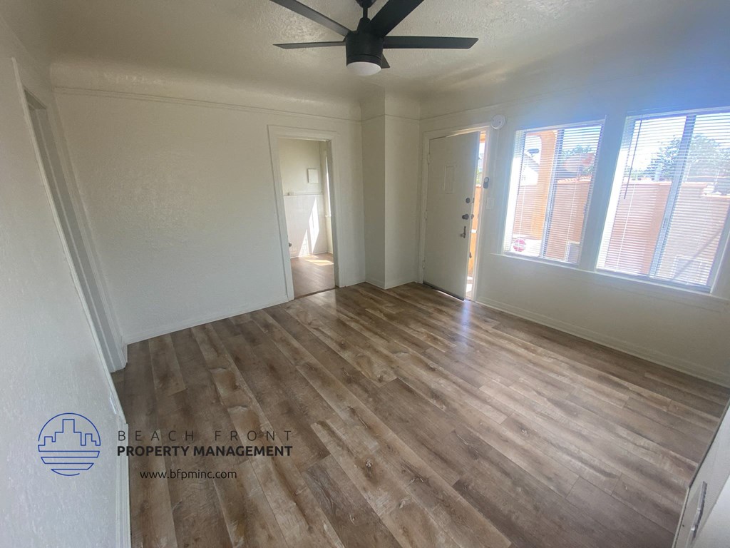 the interior of a living room with wood flooring and a ceiling fan