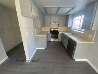 an empty kitchen with white cabinets and a window
