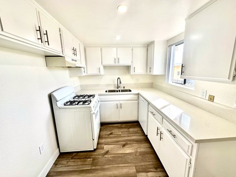 an empty kitchen with white cabinets and a window