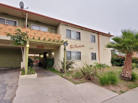 a building with a sidewalk and palm trees in front of it