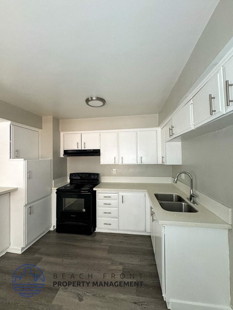 A kitchen with black appliances and white cabinets.