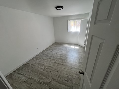 A room with a wooden floor and a door on the right side.