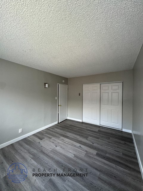 an empty living room with a white door and wood floors