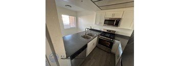 A kitchen with a stove, sink, and cabinets.
