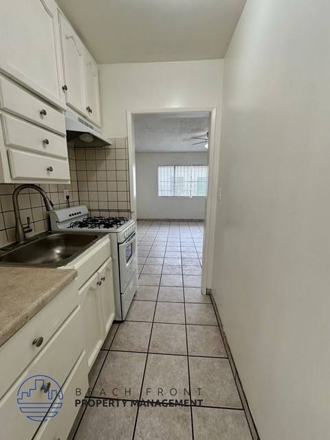 A kitchen with white cabinets and a tile floor.