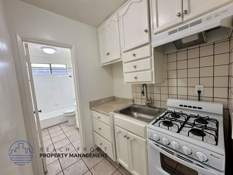 A small kitchen with a white stove and white cabinets.
