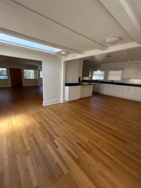 A spacious kitchen with wooden floors and white walls.