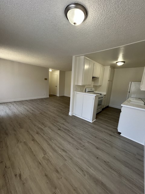 A kitchen with white appliances and wooden floors.