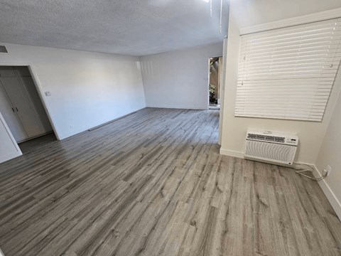 an empty room with white walls and wood floors