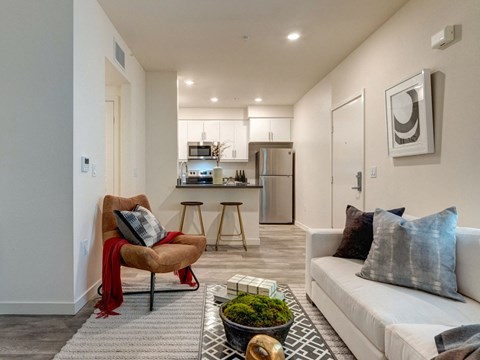 a living room with a couch and a chair in front of a kitchen