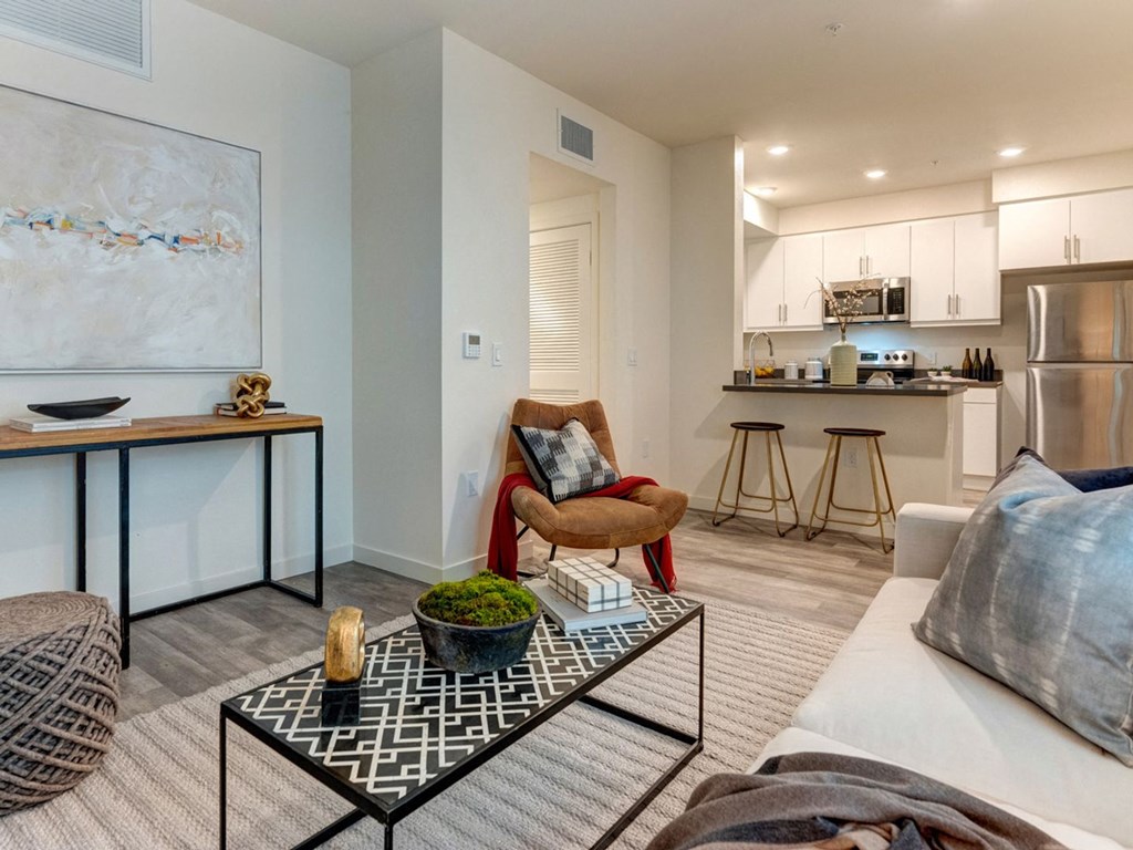 a living room with a couch and a coffee table in front of a kitchen
