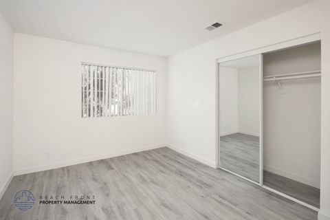 A sparsely furnished room with a sliding door and a window with bars.