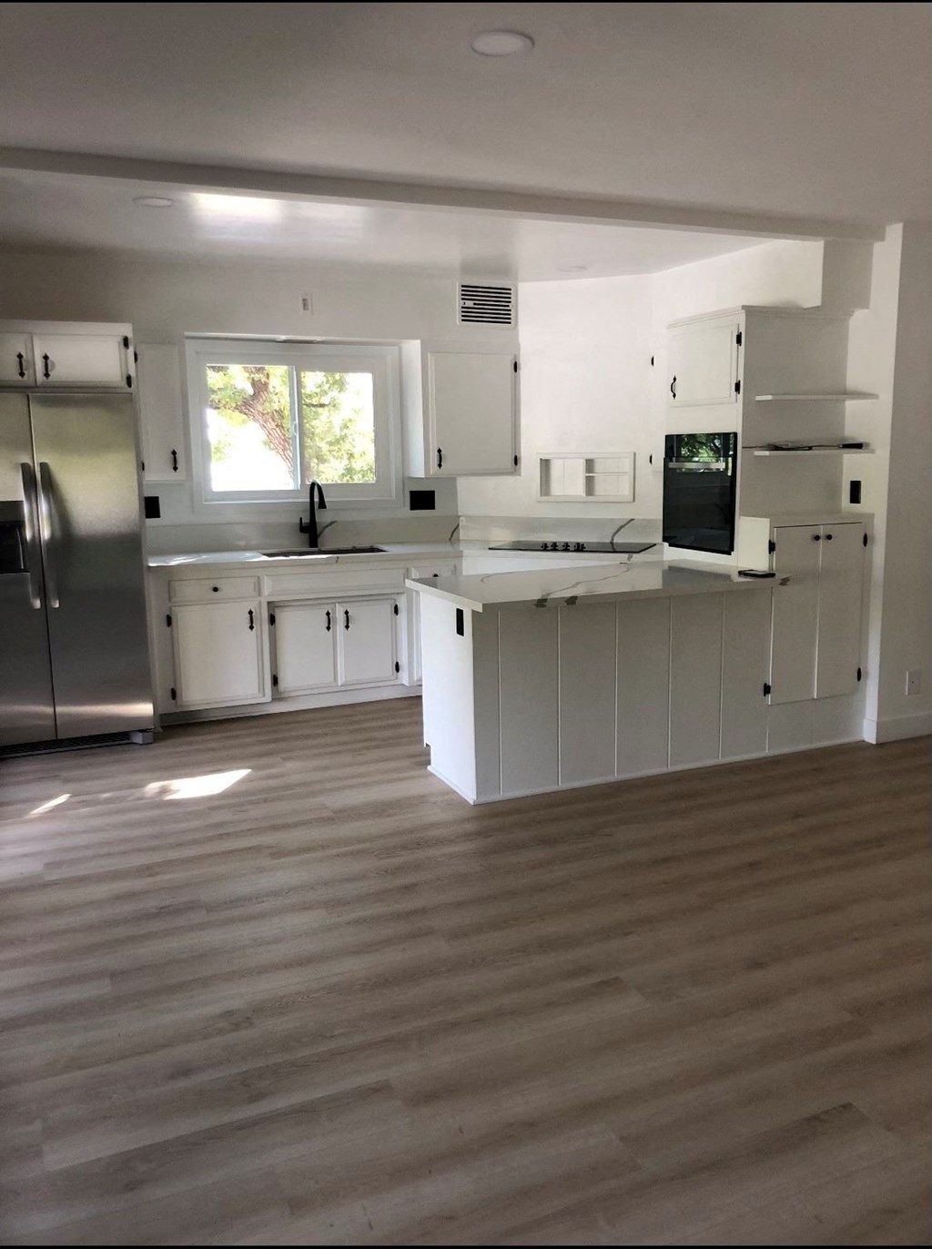 an empty kitchen with white cabinets and a refrigerator