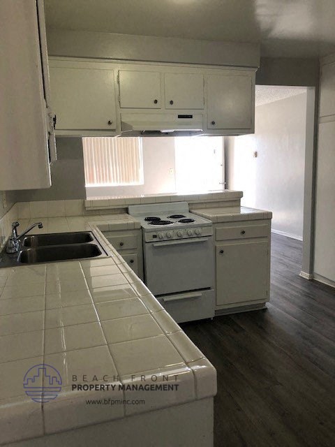 an empty kitchen with white appliances and white cabinets