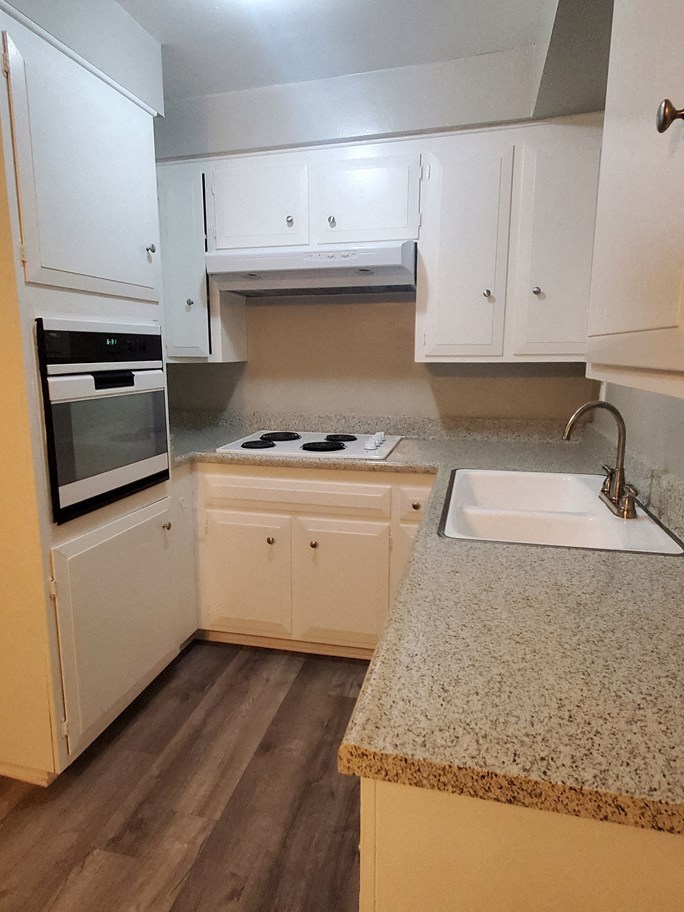 a kitchen with white cabinets and a counter top and a sink