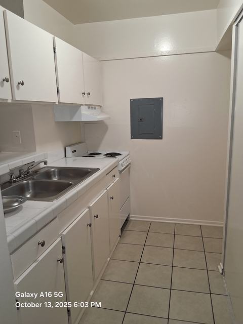 A kitchen with white cabinets and a white stove top oven.