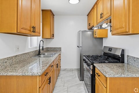 A kitchen with granite countertops and wooden cabinets.