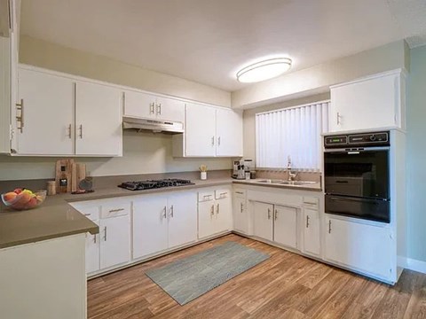 A kitchen with white cabinets and a wooden floor.