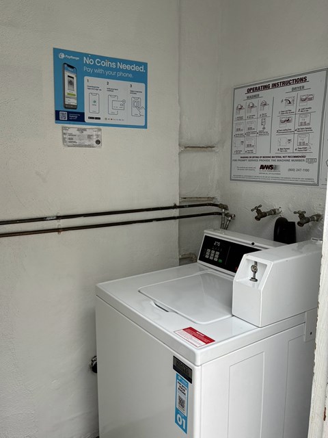 A washing machine with a sign that says "No Coins Needed" on the wall behind it.