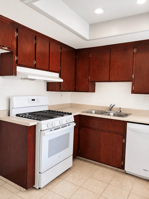 A kitchen with white appliances and brown cabinets.