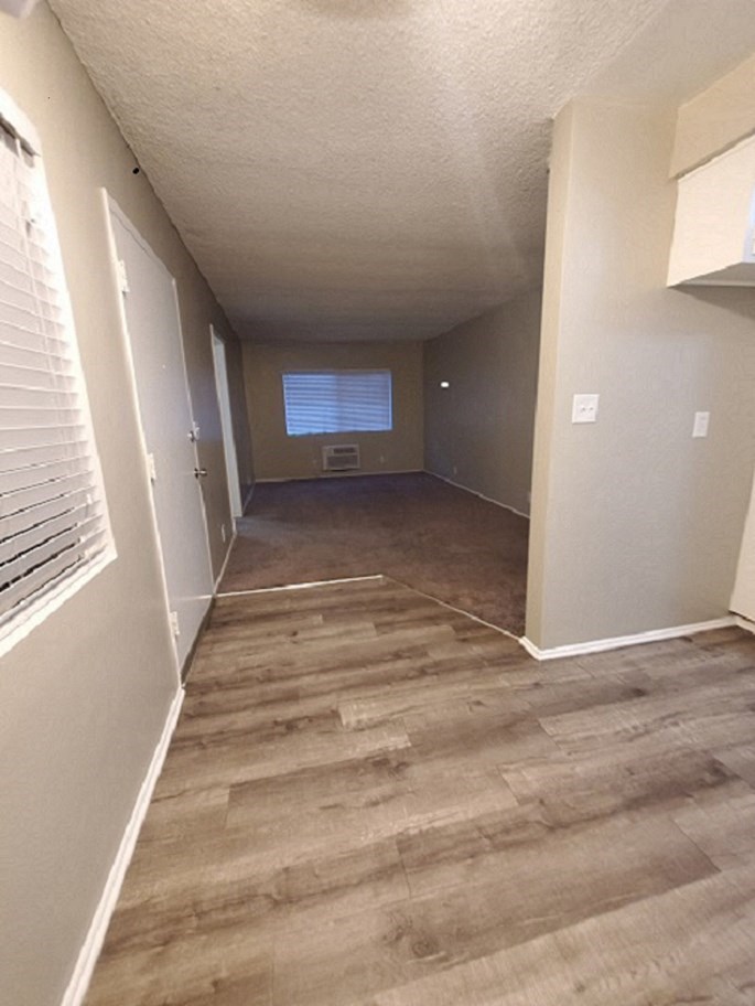an empty hallway with wood flooring and a window
