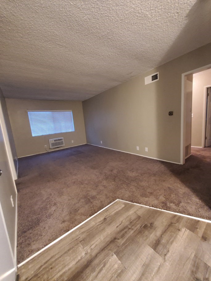 an empty living room with wood floors and a window