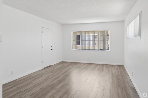 A room with a window and a wooden floor.