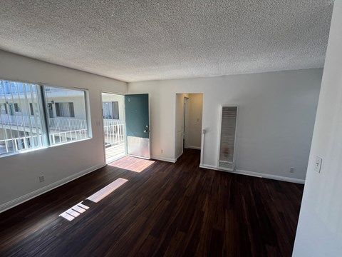 an empty living room with wood flooring and a balcony