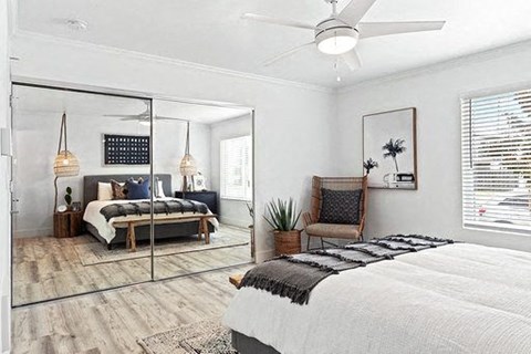 A bedroom with a bed, chair, and a mirror.