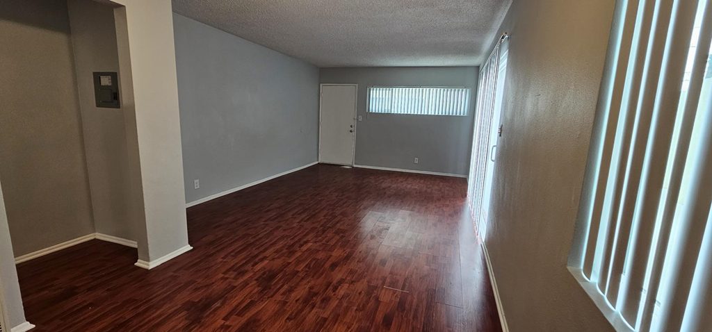 an empty living room with wood floors and a window