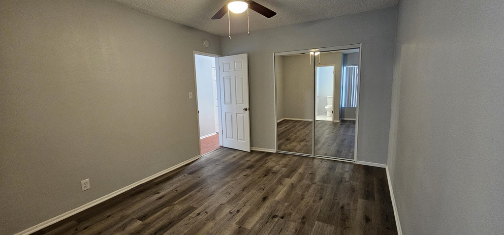 an empty living room with wood floors and a ceiling fan