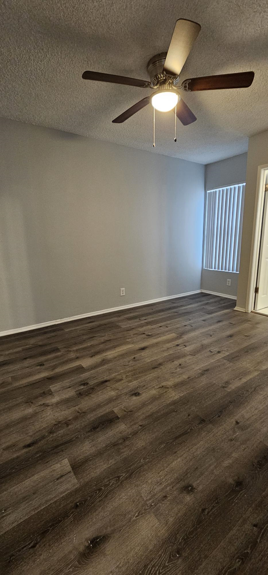 a living room with wood floors and a ceiling fan